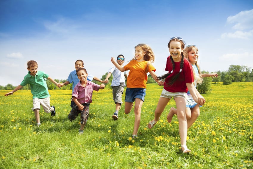 Group of kids running through a park.